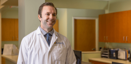 A foot and ankle doctor standing at a medical desk.