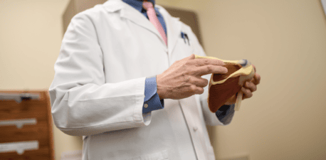 A surgeon holding a model of a shoulder joint.