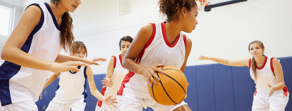 Women playing basketball on an indoor court.