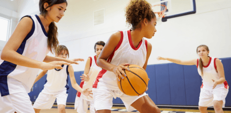 Women playing basketball on an indoor court.