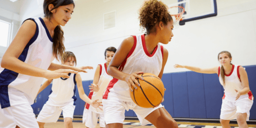 Women playing basketball on an indoor court.